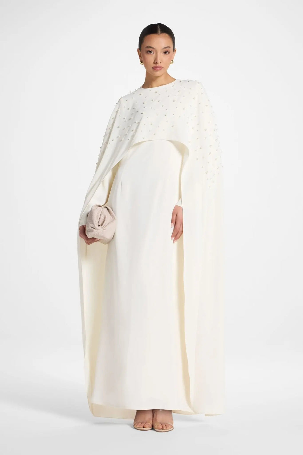 Woman wearing a long, light-colored dress with a plain background