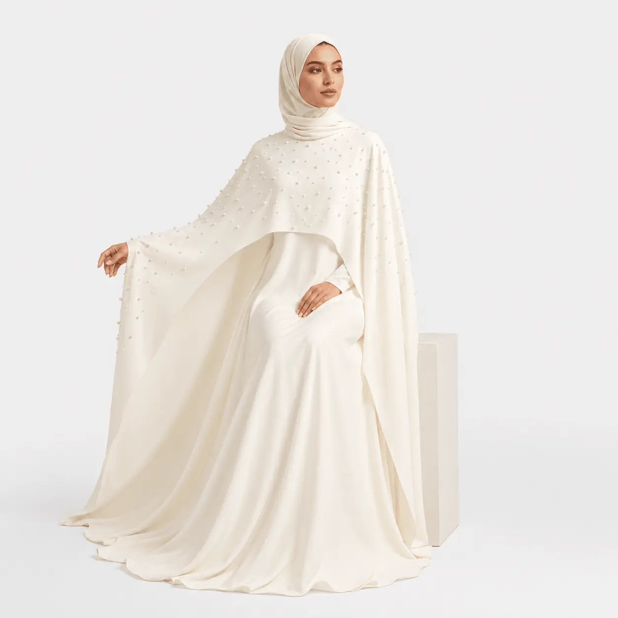 Woman wearing a white abaya with a matching hijab on a white background