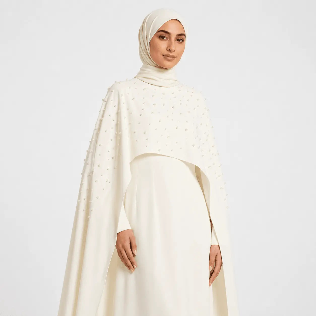 Woman wearing a cream-colored hijab and dress on a white background