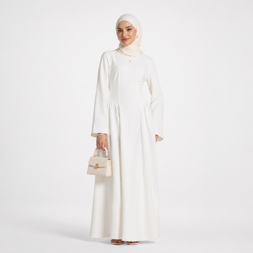 Woman wearing a white abaya and hijab holding a beige handbag on a white background