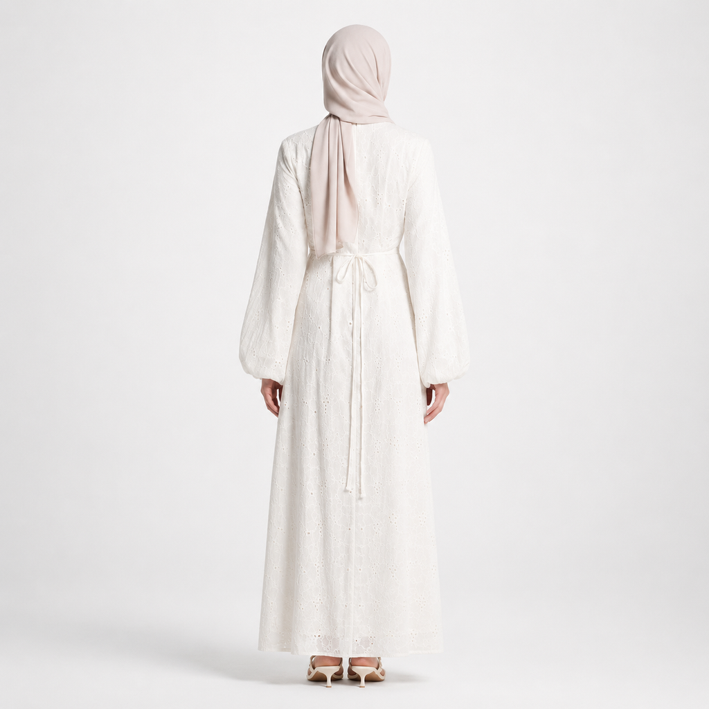 Person wearing a long white dress and headscarf on a plain background