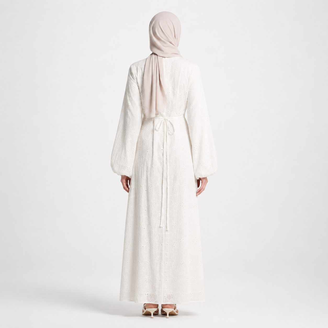 Person wearing a long white dress and headscarf on a plain background