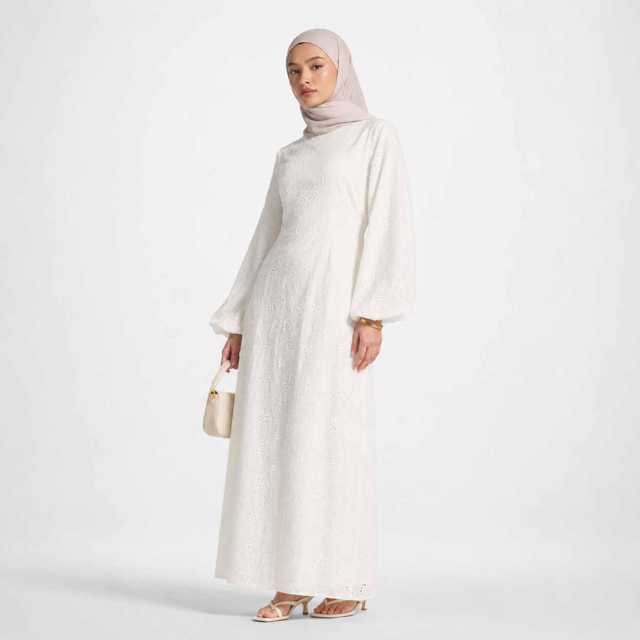 Woman wearing a white dress and hijab on a light gray background