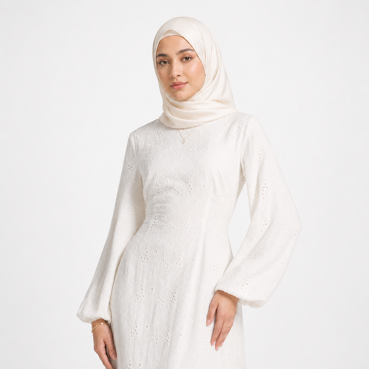 Woman wearing a white dress and hijab on a light gray background