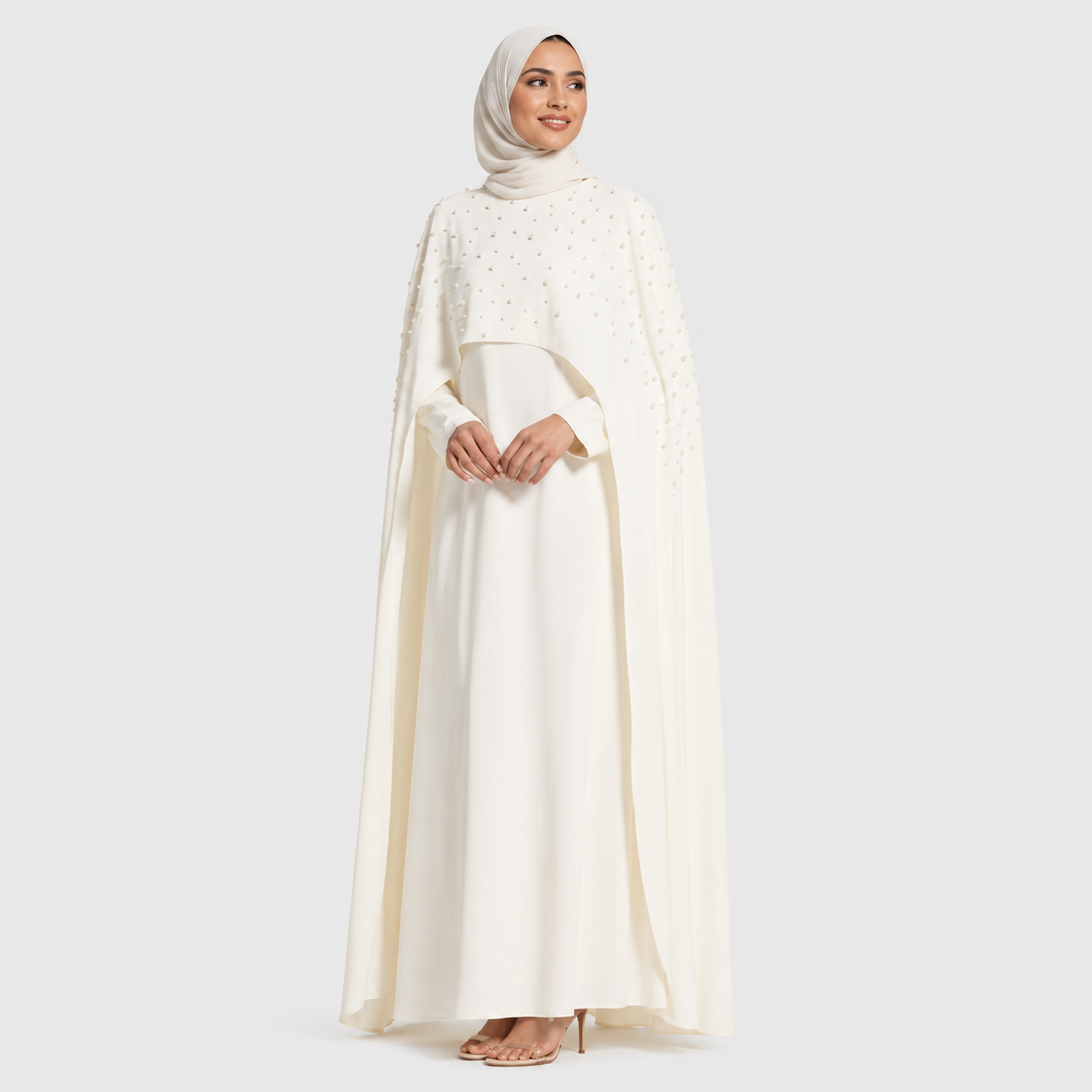 Woman wearing a long, light-colored dress with a matching hijab on a white background