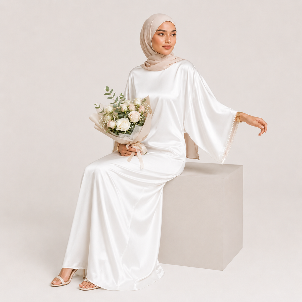Woman in a white dress holding flowers on a plain background