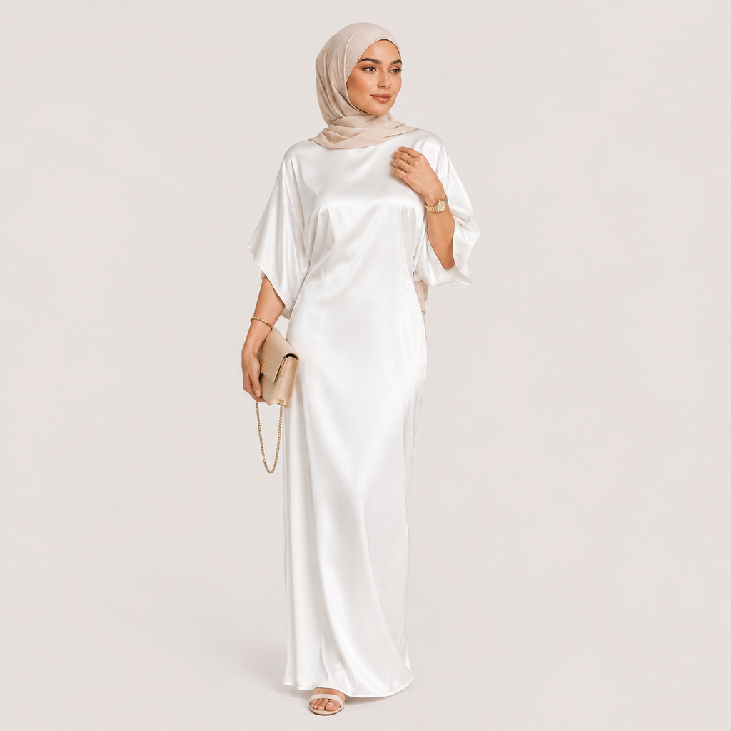 Woman wearing a white dress and hijab on a light pink background
