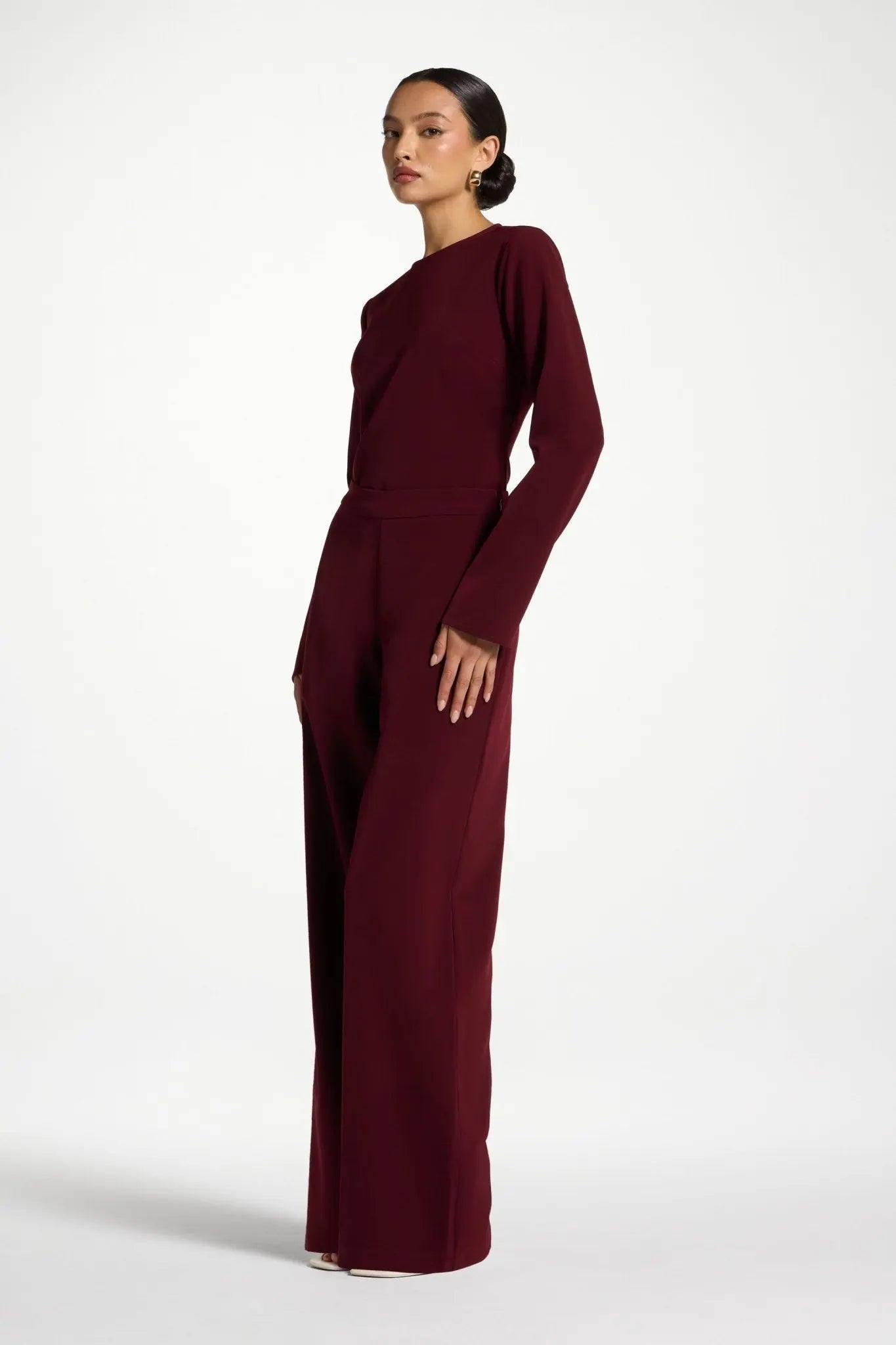 Woman wearing a burgundy jumpsuit on a white background