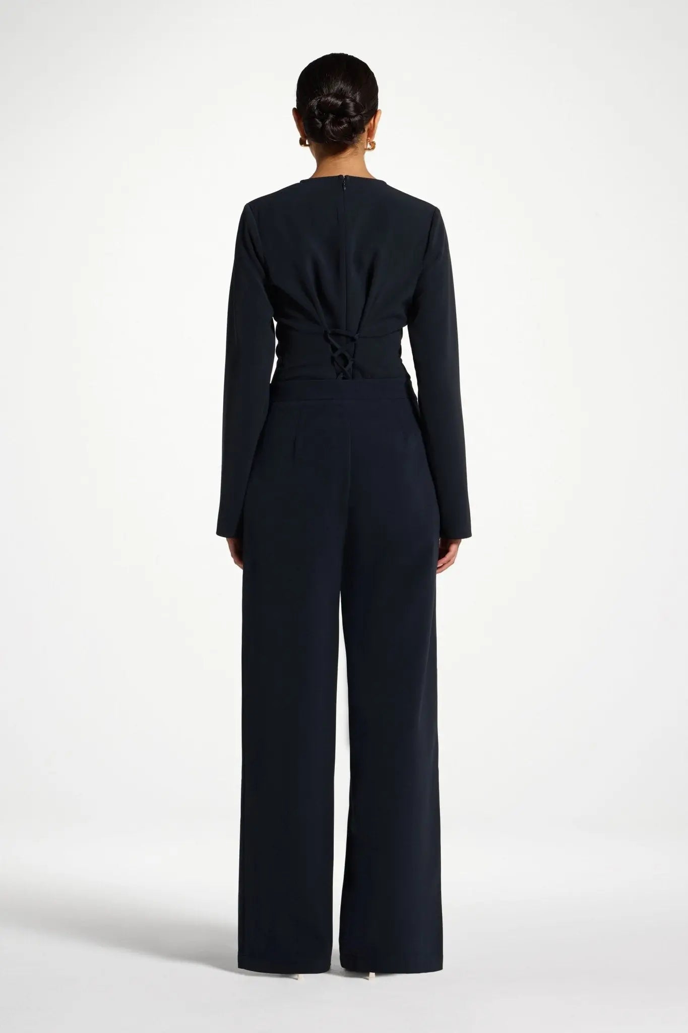 Person wearing a navy blue jumpsuit on a white background